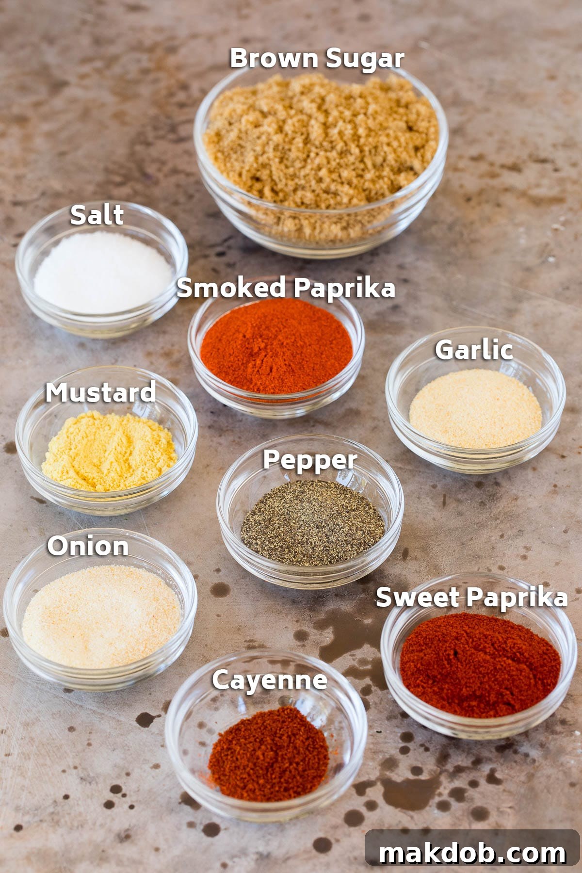Small glass bowls containing various herbs and spices, meticulously arranged to showcase the individual components of the smoked turkey rub recipe.