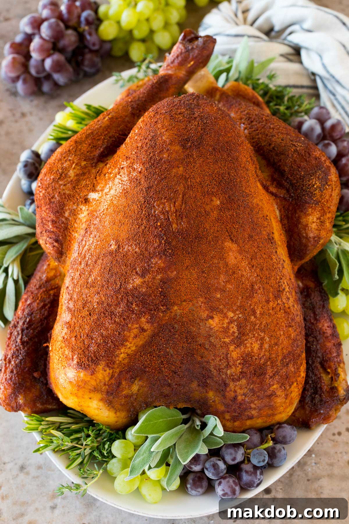 A perfectly cooked and sliced smoked turkey, showcasing its golden-brown skin and juicy interior, garnished with fresh herbs on a serving platter.