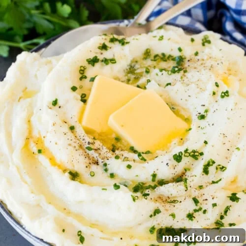 Velvety Sour Cream Mash 7 A bowl of sour cream mashed potatoes topped with butter and herbs.