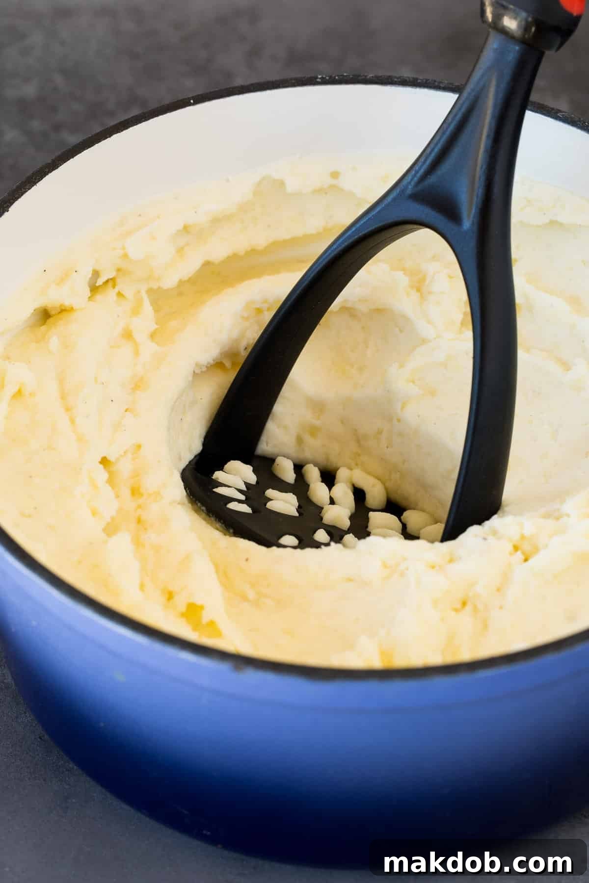 Velvety Sour Cream Mash 5 A potato masher in a pot of potatoes.