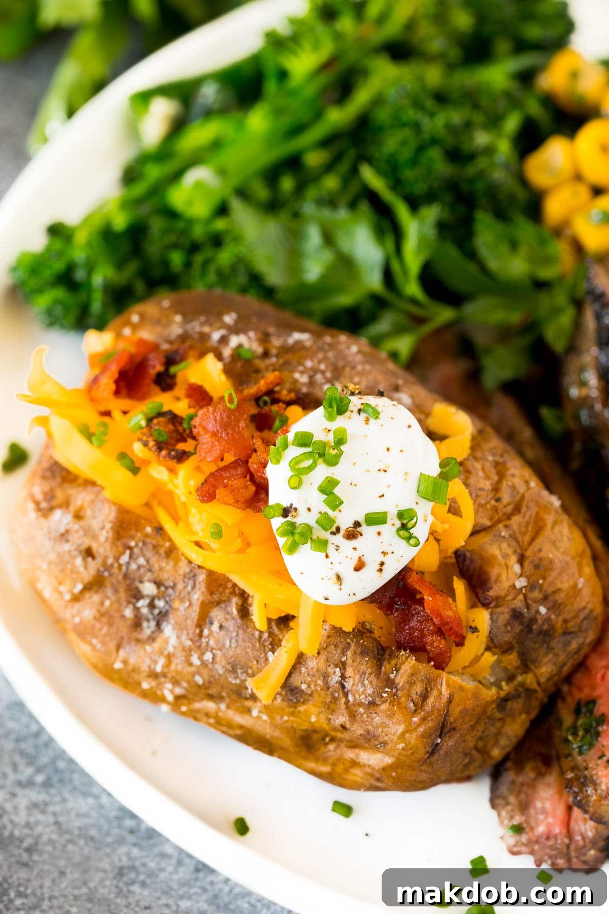 Air fryer baked potatoes served with steak and vegetables.