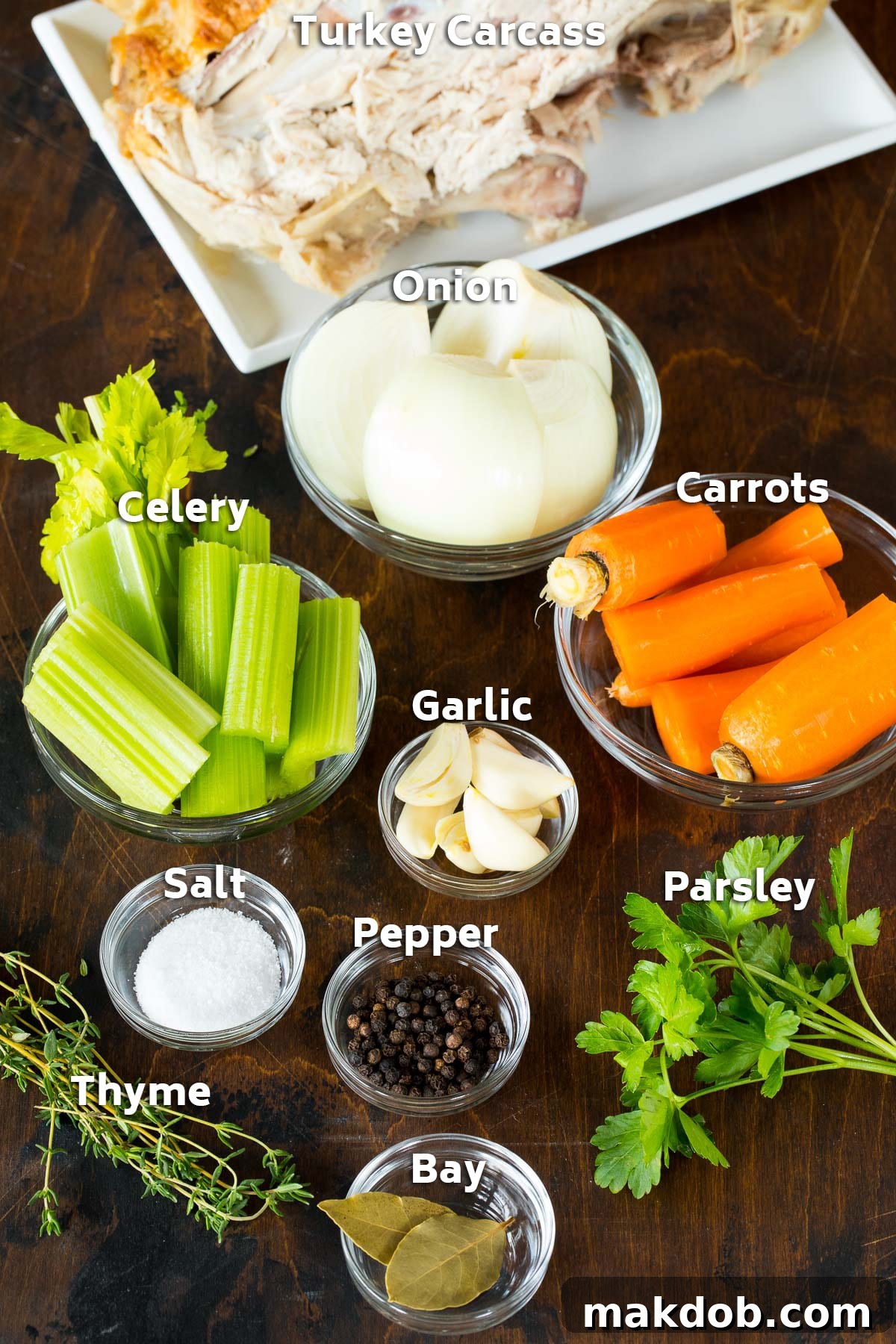 Ingredients laid out for making rich, homemade turkey broth, including a turkey carcass, various vegetables, and fresh herbs.