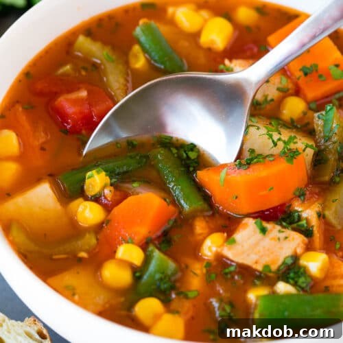 A bowl of turkey vegetable soup with a spoon in it.