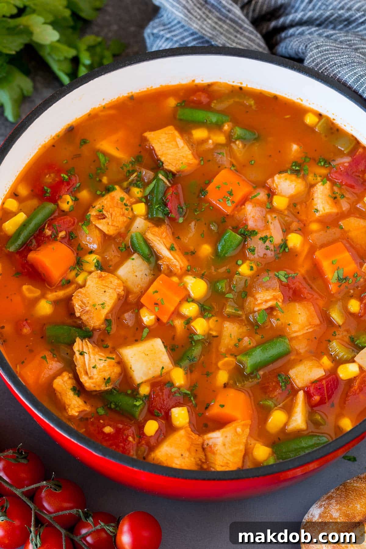 A large pot of turkey vegetable soup, richly colored and steaming, with a generous garnish of fresh parsley on top, ready to be served.
