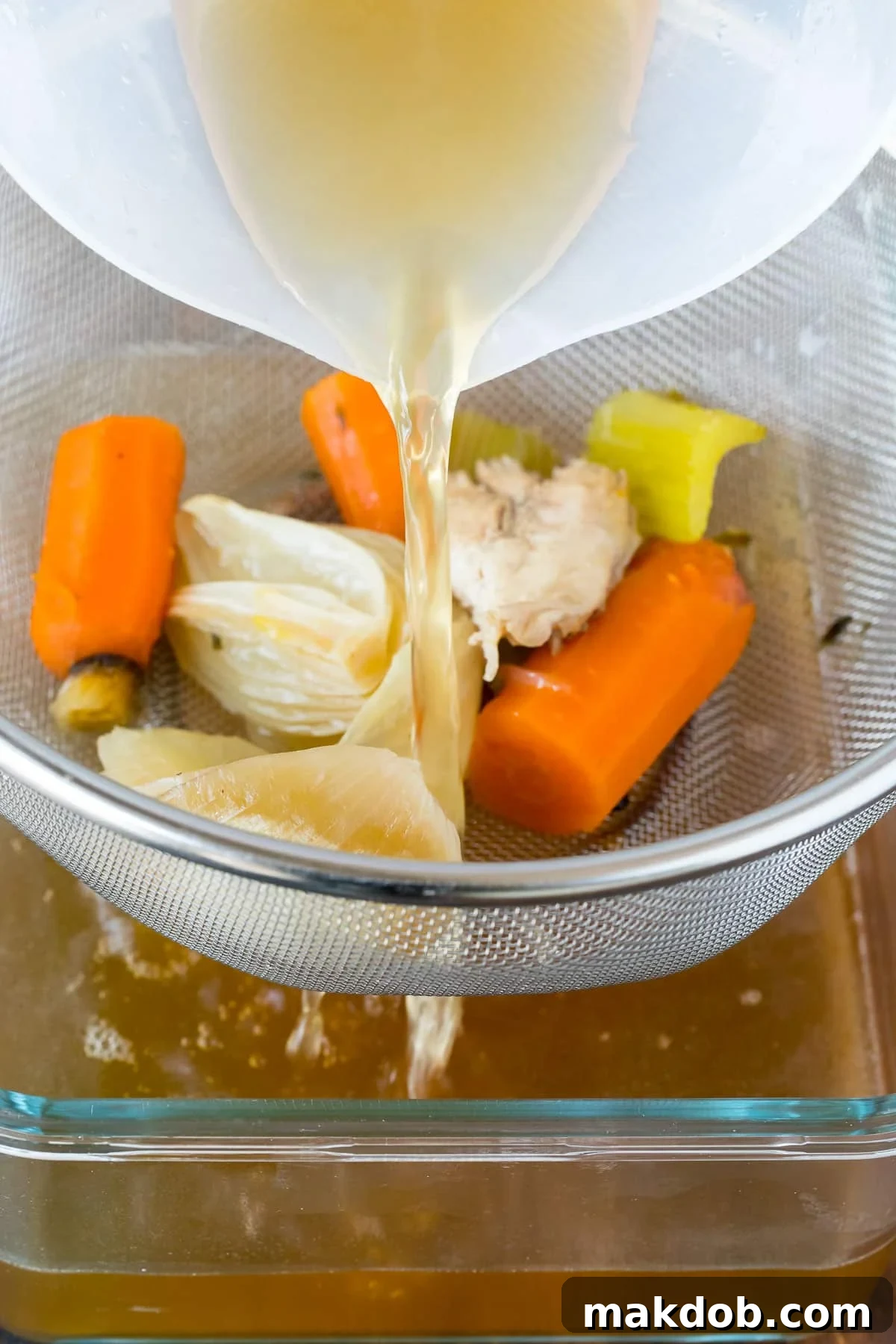 Straining Turkey Broth Broth being poured through a mesh strainer.