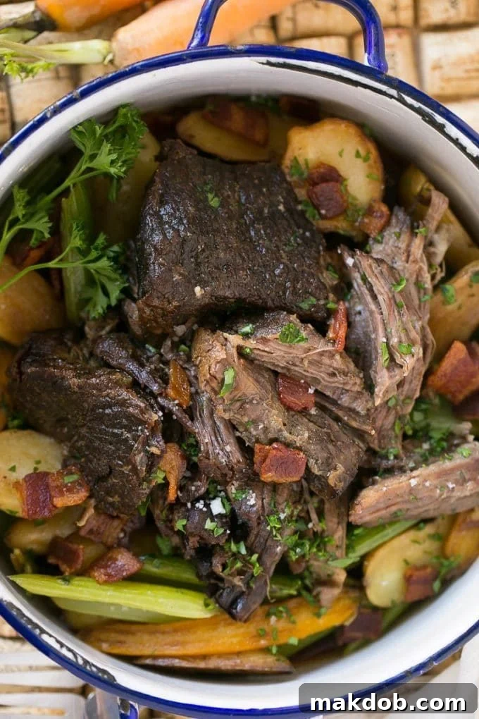 A large pot brimming with a savory beef roast, vibrant carrots, crisp celery, and tender potatoes in a rich braising liquid.