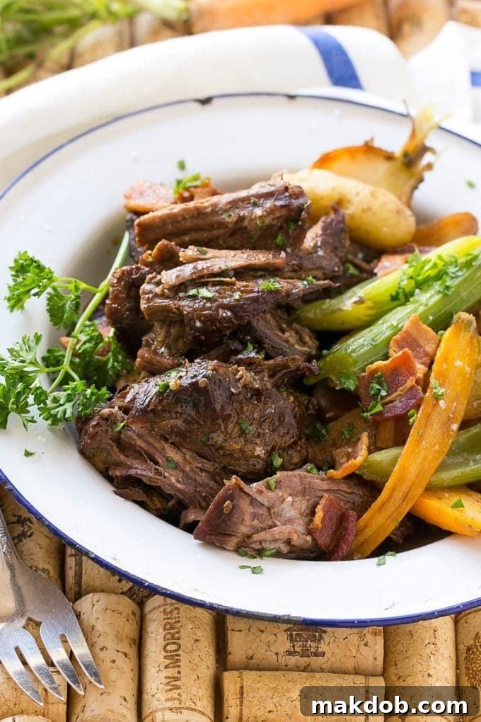 A close-up shot of a plate of perfectly shredded Yankee pot roast, accompanied by tender vegetables and sprinkled with crispy bacon bits.