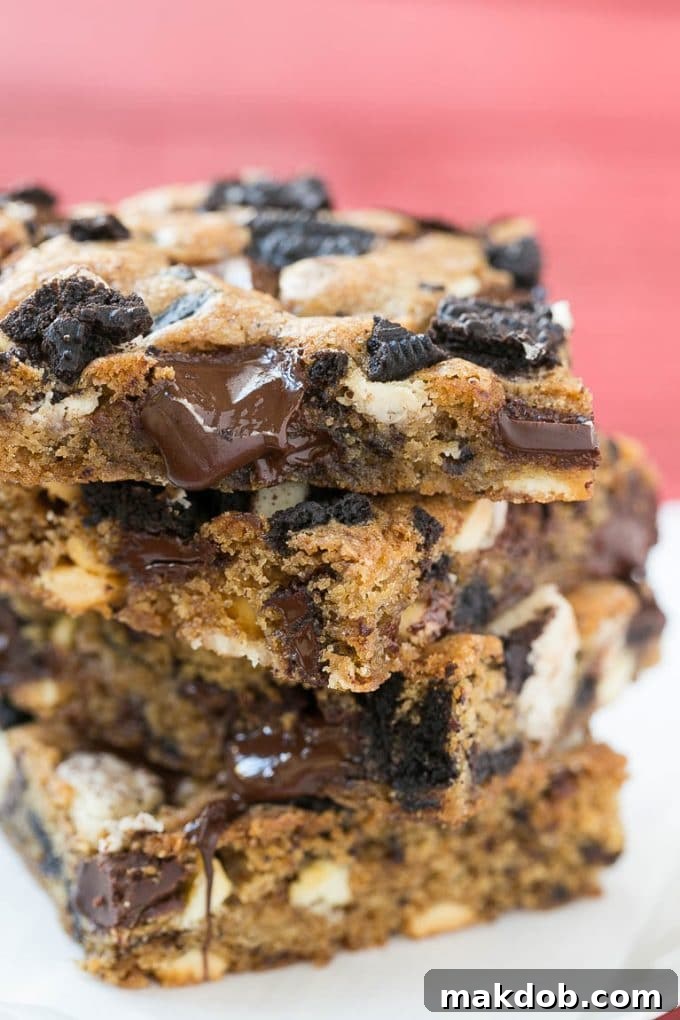 A stack of golden blondies filled with gooey chocolate chunks and delicious chopped Oreo cookies, ready to be enjoyed.