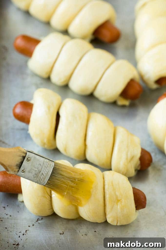 Hot dogs in dough brushed with egg wash.