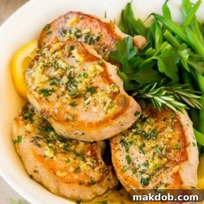 Baked boneless pork chops in a serving platter with herbs and green beans.