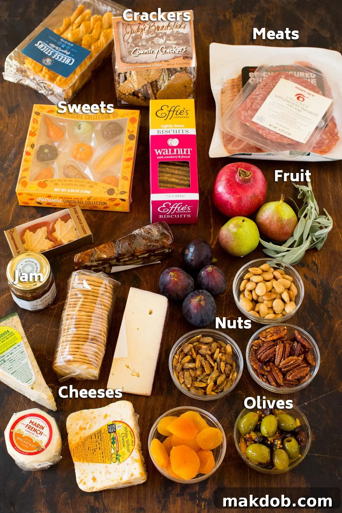 Assorted packages of crackers, nuts, olives, and various cheeses, representing the diverse ingredients for a charcuterie board.
