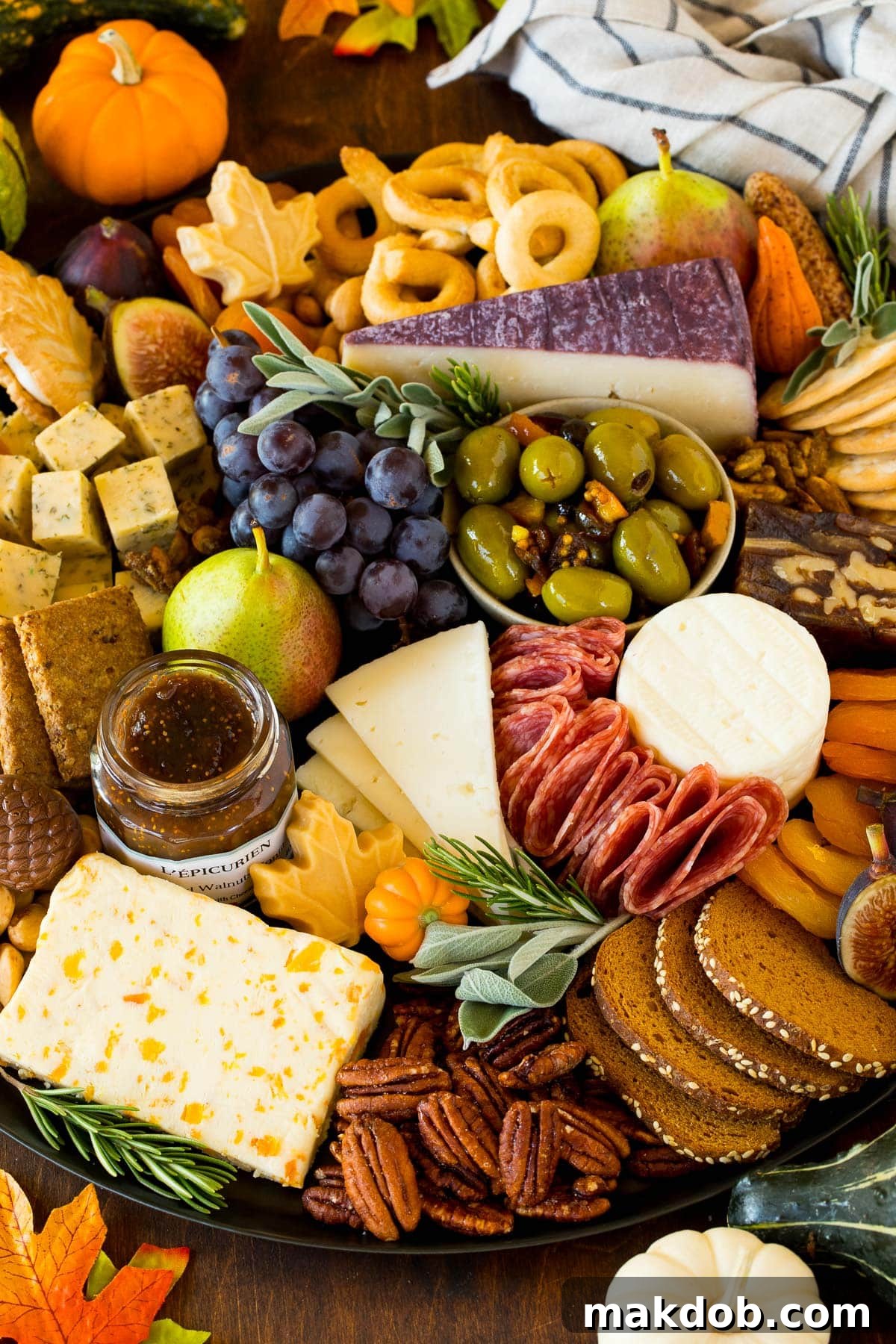 A Thanksgiving charcuterie board generously filled with various meats, cheeses, and autumnal fruits, ready to be served.