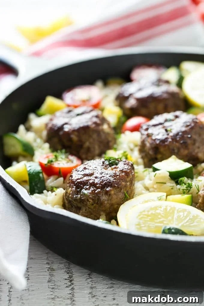 A pan of Greek style meatballs with lemon dill rice, fresh tomatoes, and zucchini.
