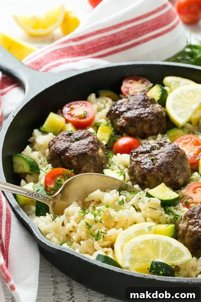 A serving spoon lifting Greek meatballs and rice from a dish.