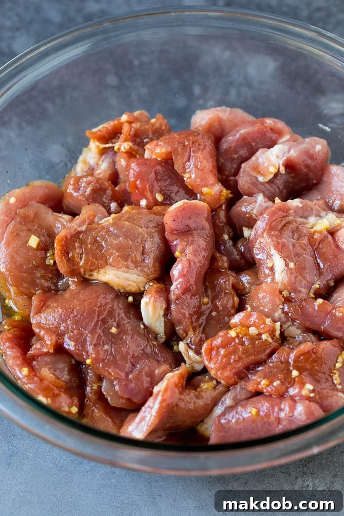 A close-up shot of thinly sliced pork tenderloin marinating in a rich, dark sauce, promising deep flavors for the Banh Mi sandwich.