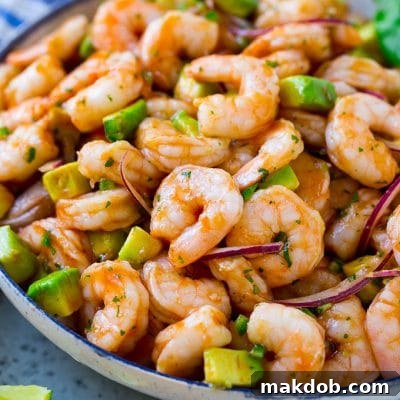 A vibrant serving bowl of authentic Mexican shrimp cocktail, filled with small shrimp, diced avocado, fresh herbs, and sliced jalapeno, ready to be enjoyed as a refreshing appetizer.