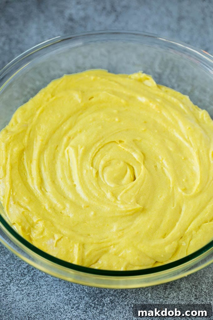 Lemon cake batter being mixed in a bowl, showcasing its smooth texture before baking.