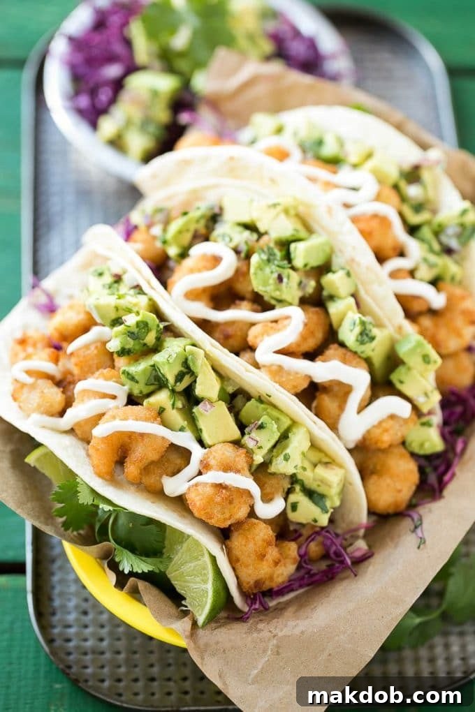 A basket of crispy fried shrimp tacos with avocado salsa, ready to serve.