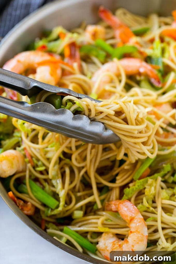 A vibrant close-up of a generous pile of Shrimp Chow Mein, showcasing tender shrimp, perfectly coated noodles, and crisp vegetables.