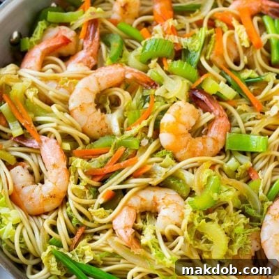 A pan of shrimp chow mein noodles with vegetables.