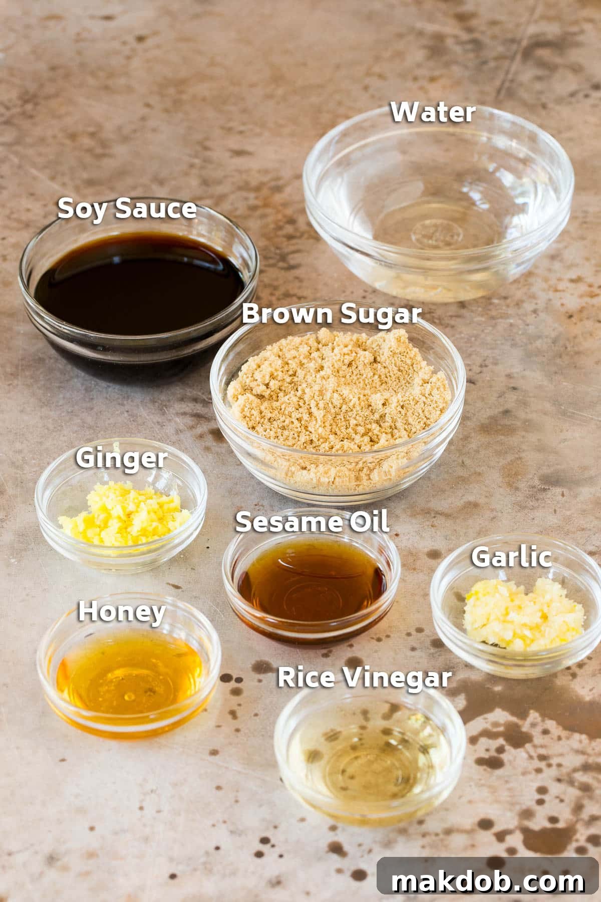 Bowls showcasing individual ingredients for teriyaki marinade, including low sodium soy sauce, brown sugar, minced garlic, and fresh ginger.
