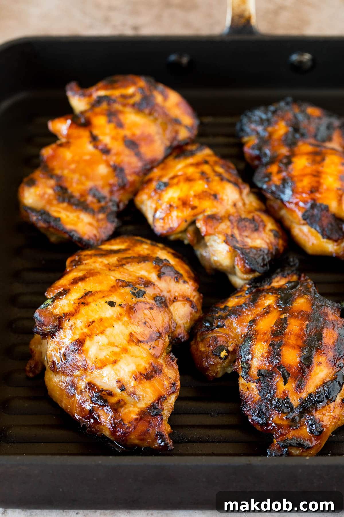 Teriyaki chicken cooking on a grill pan, showing a beautiful caramelized glaze.