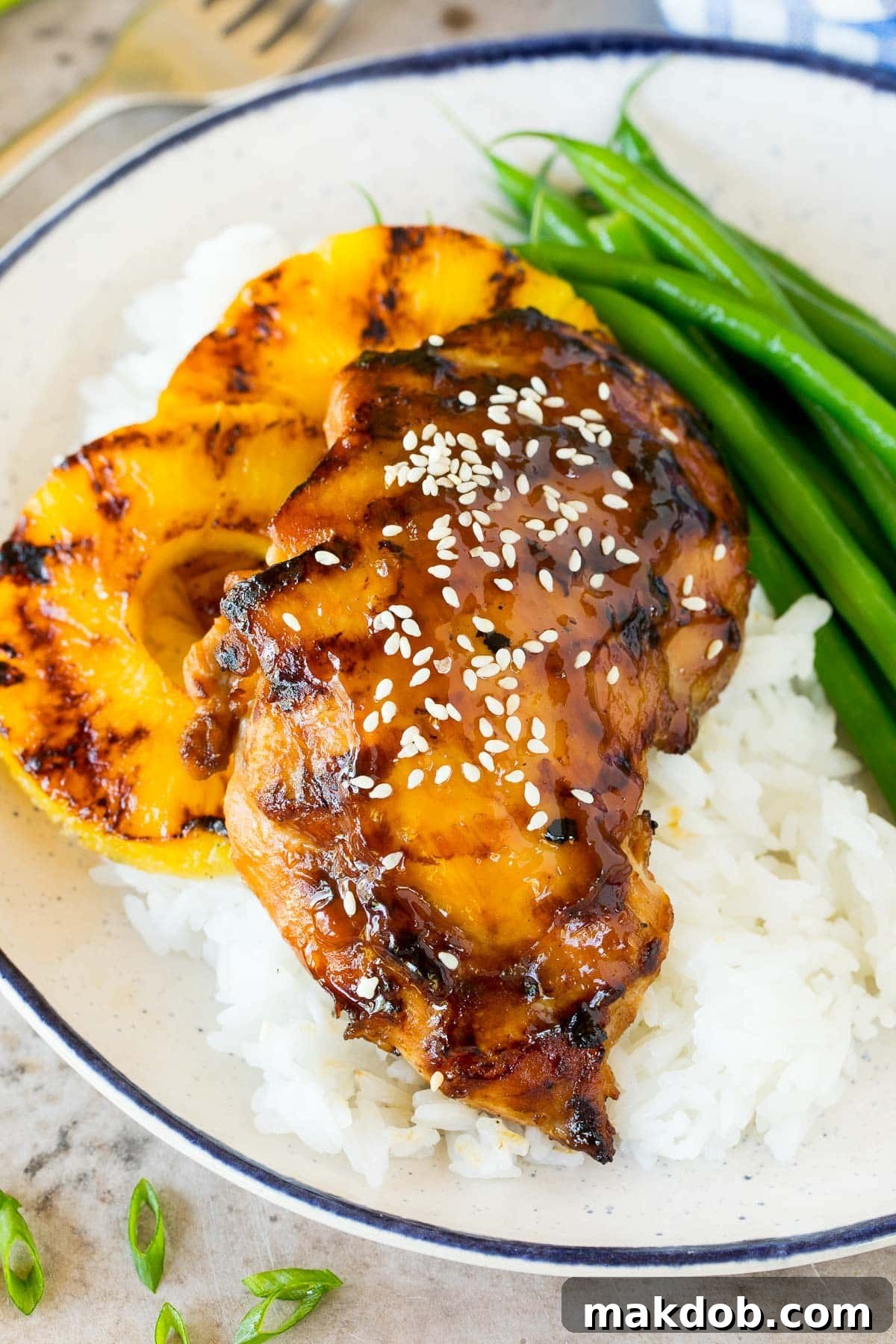 Teriyaki flavored chicken served on a plate with fluffy rice and green beans, showcasing a complete meal.