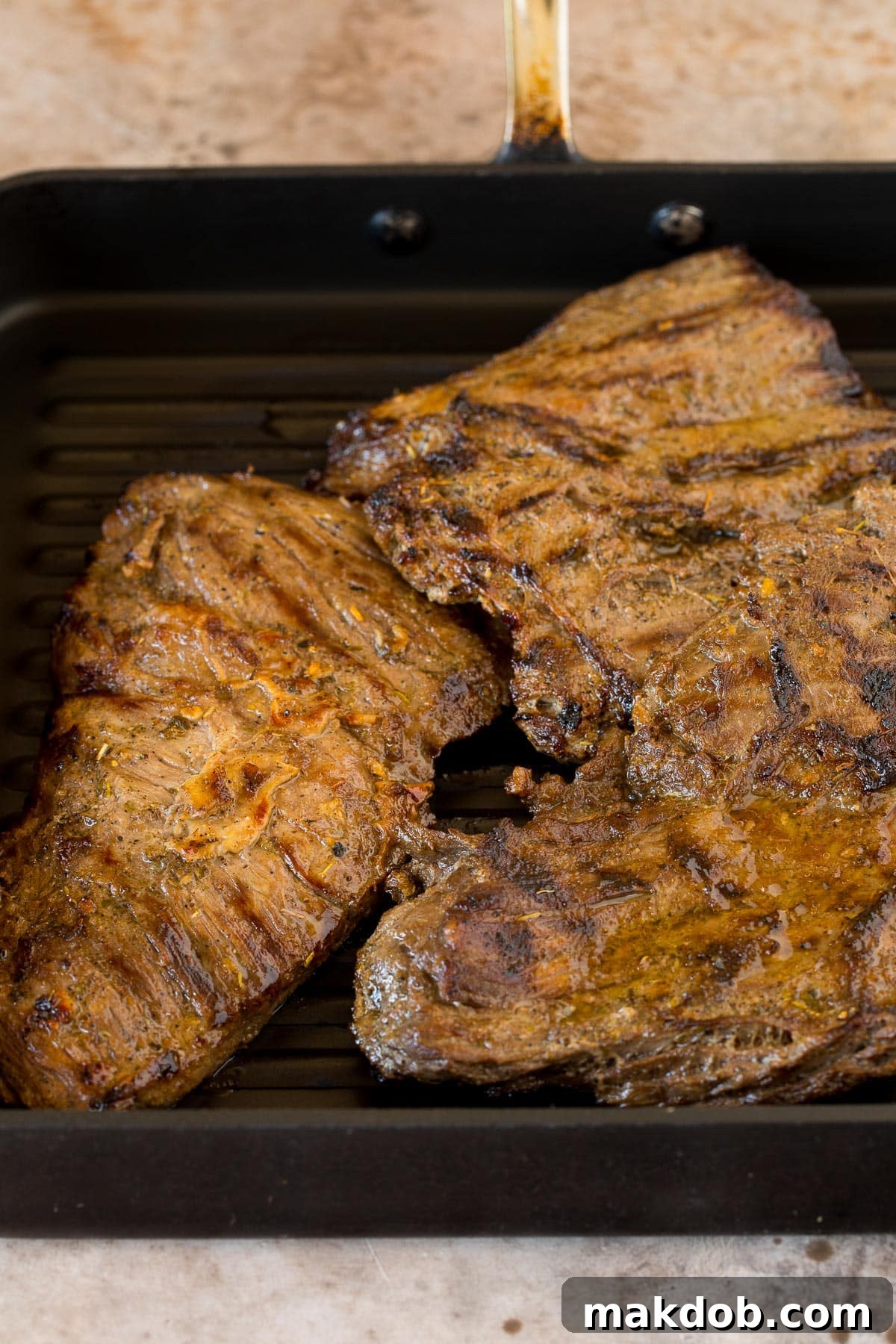 Next-Level Skirt Steak Marinade 5 Grilled skirt steak cooking in a cast iron grill pan, showing beautiful char marks.