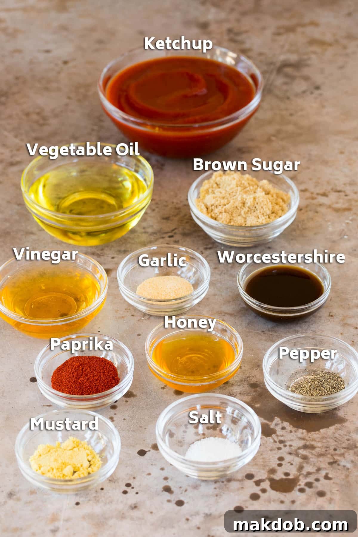 Separate bowls displaying the key ingredients for BBQ chicken marinade: ketchup, vegetable oil, and various spices and seasonings.