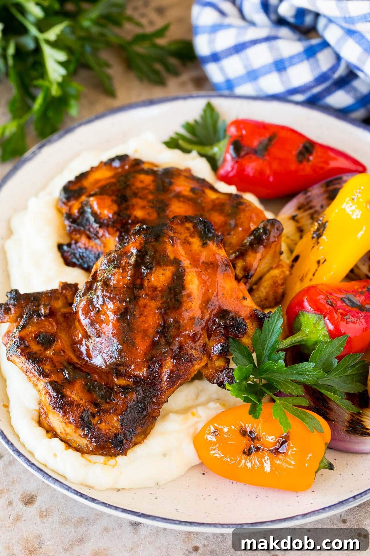 Grilled chicken thighs, marinated in delicious BBQ chicken marinade, served beautifully with creamy mashed potatoes and vibrant sautéed bell peppers.