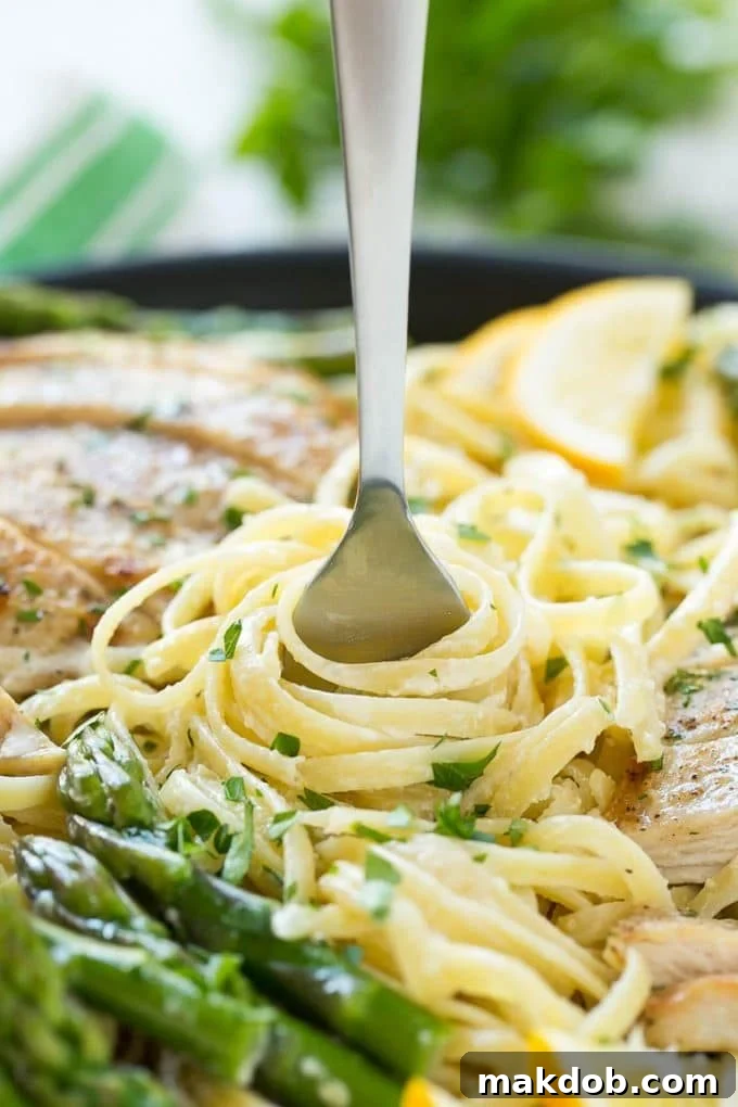 Serving Creamy Lemon Asparagus Pasta A fork lifting a generous portion of creamy lemon asparagus pasta, showcasing the rich sauce and fresh ingredients.