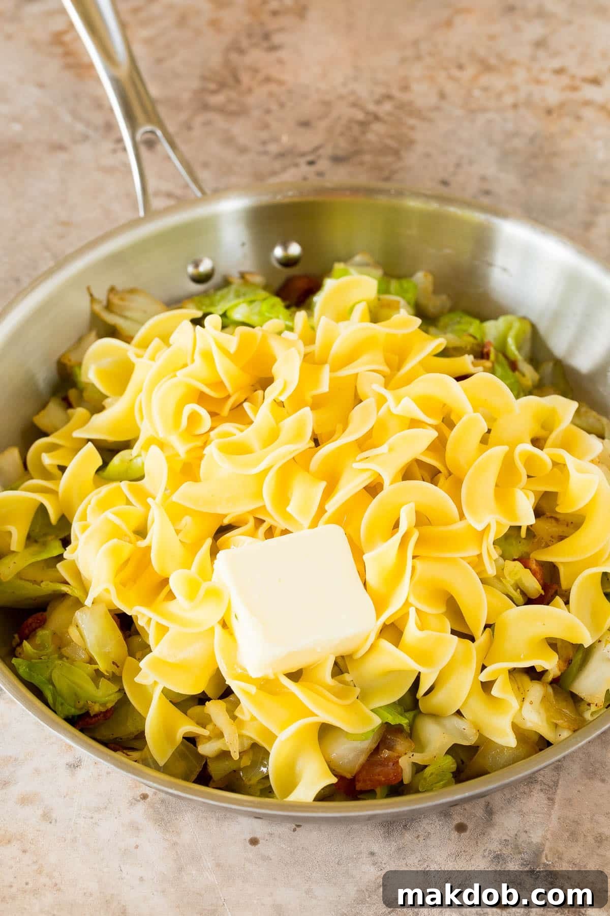 Cabbage and noodles tossed together in a skillet with melted butter and savory seasonings.