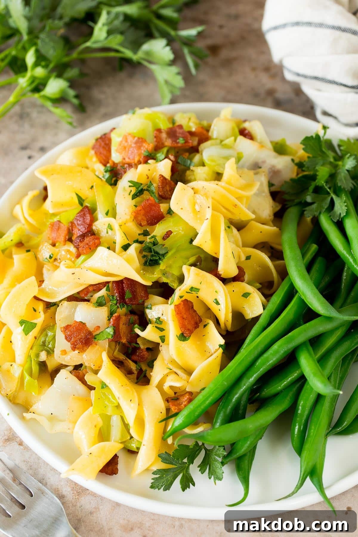 A plate of Haluski served with a side of fresh green beans, showcasing a complete comforting meal.