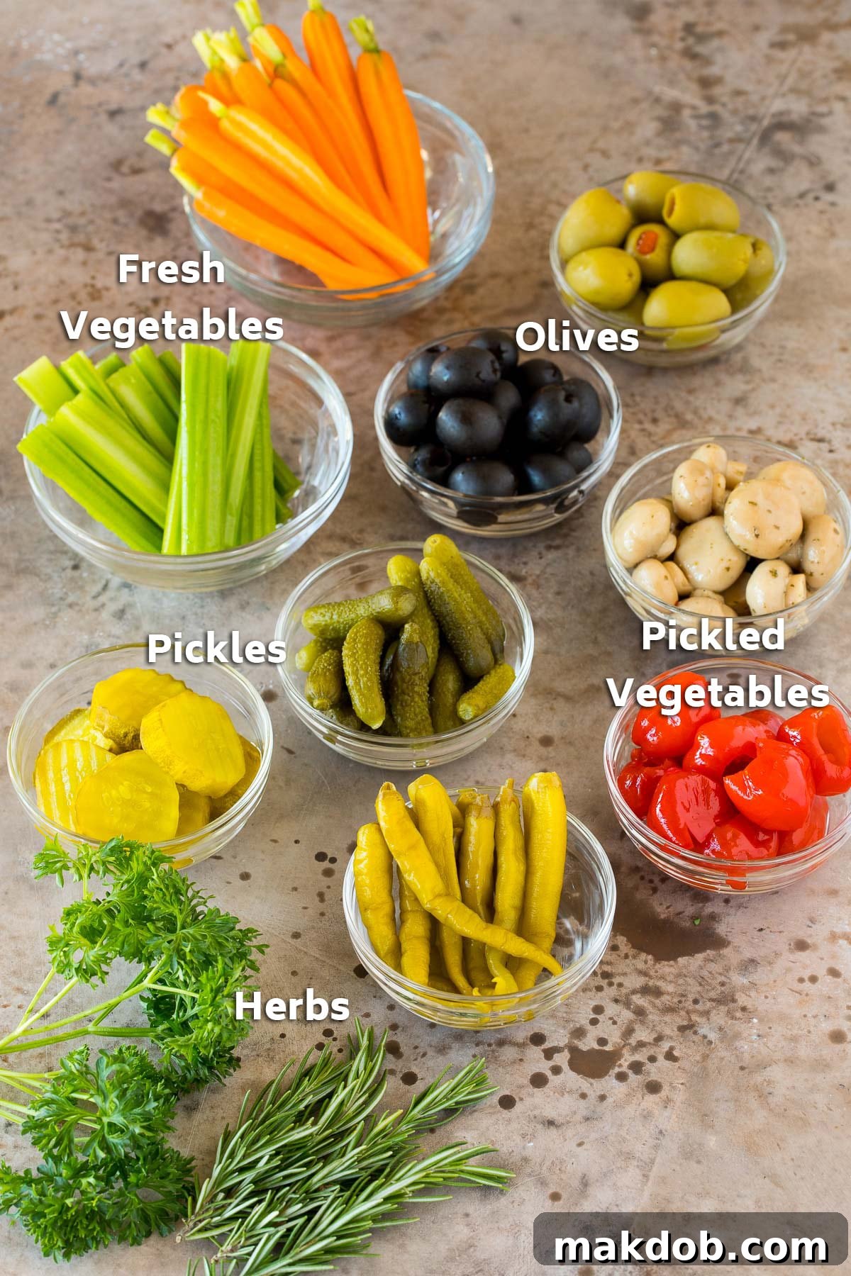 Bowls filled with an assortment of olives, crisp fresh vegetables, and a variety of pickled and marinated vegetables, ready for assembly onto a relish tray.