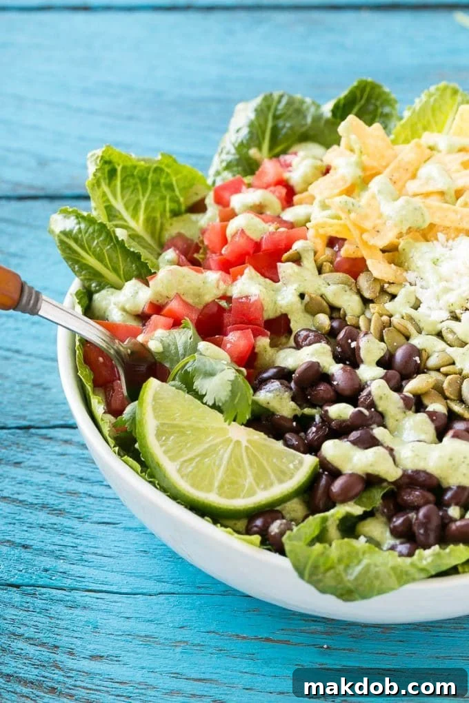 Mexican Caesar Salad Recipe | Caesar Salad | Mexican Salad #salad #beans #lunch #dinner #dinneratthezoo A fork in a bowl of Mexican style Caesar salad.