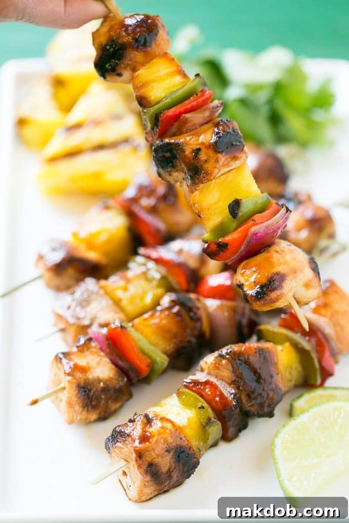 Grilled chicken and pineapple skewers interspersed with red and green bell peppers and red onion, displaying perfect char marks and a tempting glaze from the marinade.