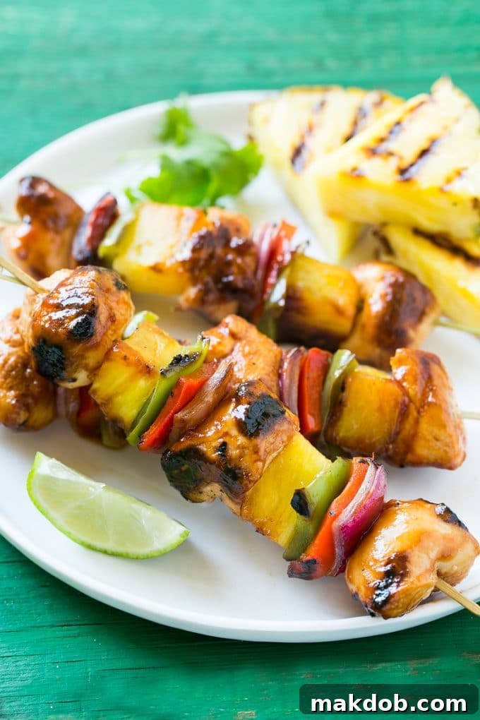 A close-up view of beautifully grilled Hawaiian chicken kabobs, highlighting the tender chicken, vibrant pineapple, and colorful vegetables, all coated in a delectable, sweet, and savory glaze.