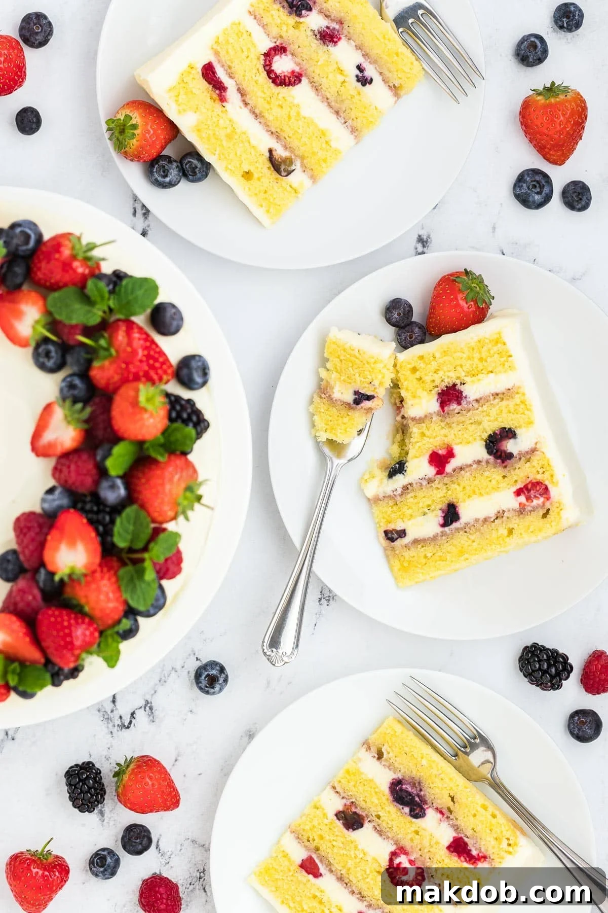 Several slices of Berry Chantilly Cake artfully arranged on a cake stand, with one slice featuring a fork, highlighting the cake's inviting layers and luscious berry and frosting filling.