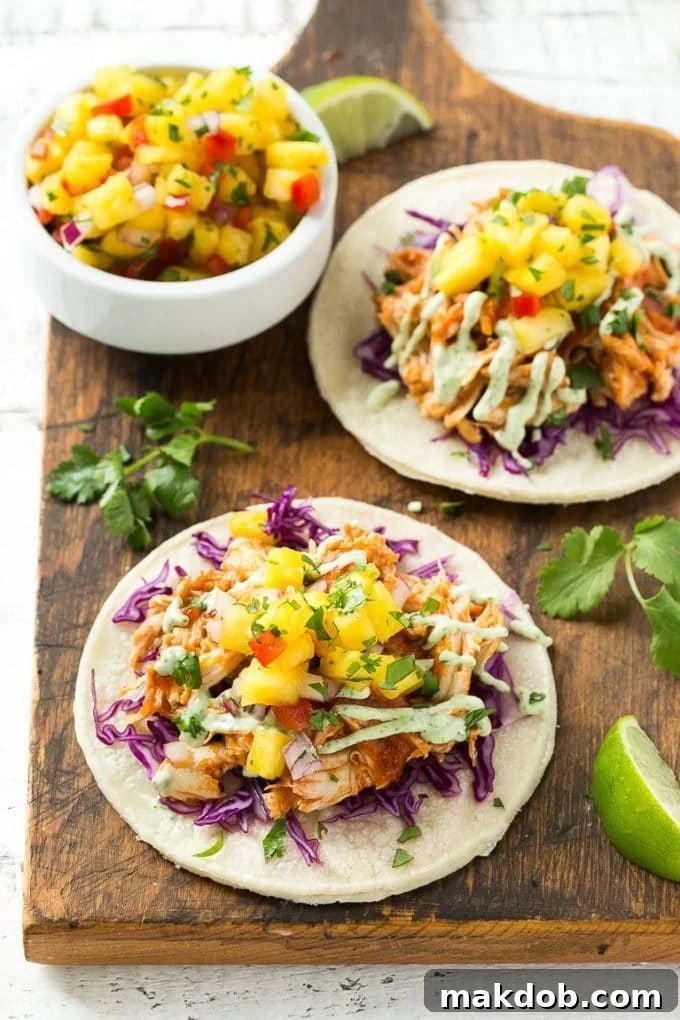 A close-up view of mini corn tortillas, stacked and generously topped with finely shredded purple cabbage and the flavorful pulled chicken.