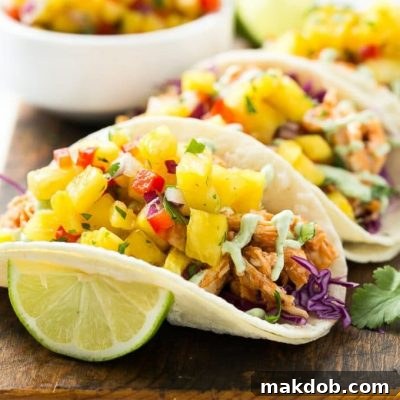 This recipe for pulled chicken tacos with pineapple salsa is flavorful shredded chicken combined topped with sweet and tangy salsa and creamy cilantro sauce, all stuffed inside warm corn tortillas.