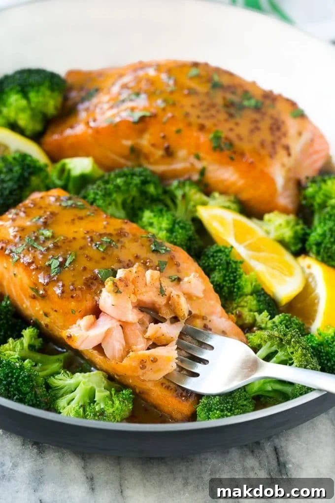 A pan of honey mustard salmon with broccoli and a fork cutting into the fish.