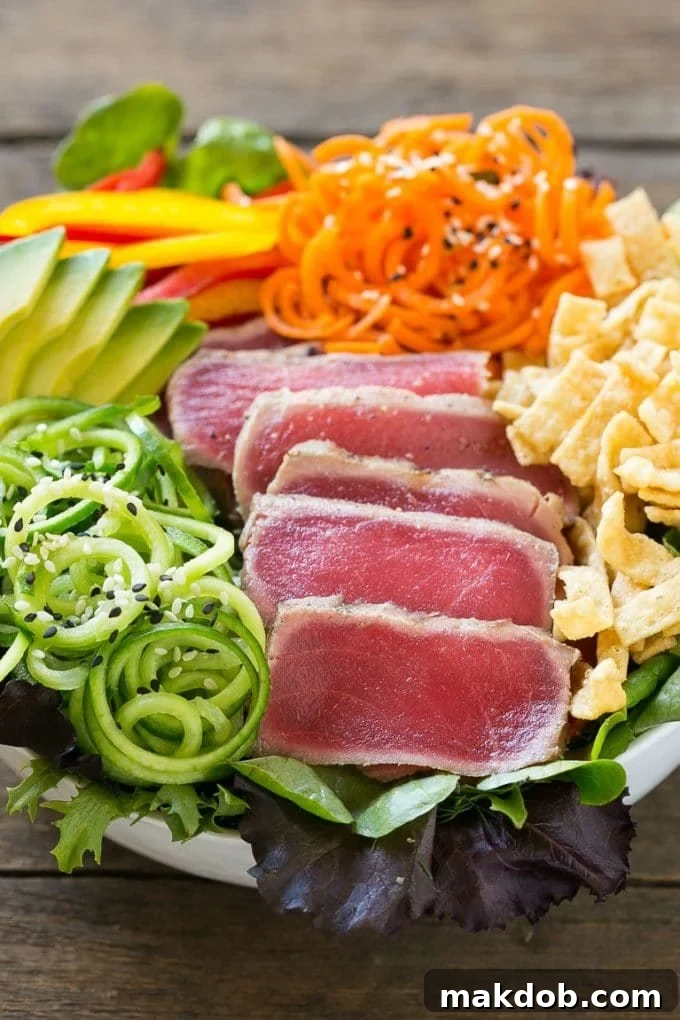 Seared Ahi Tuna Salad with Zesty Sesame Ginger Vinaigrette 4 A bowl of ahi tuna salad with thinly sliced seared tuna and an assortment of colorful veggies.