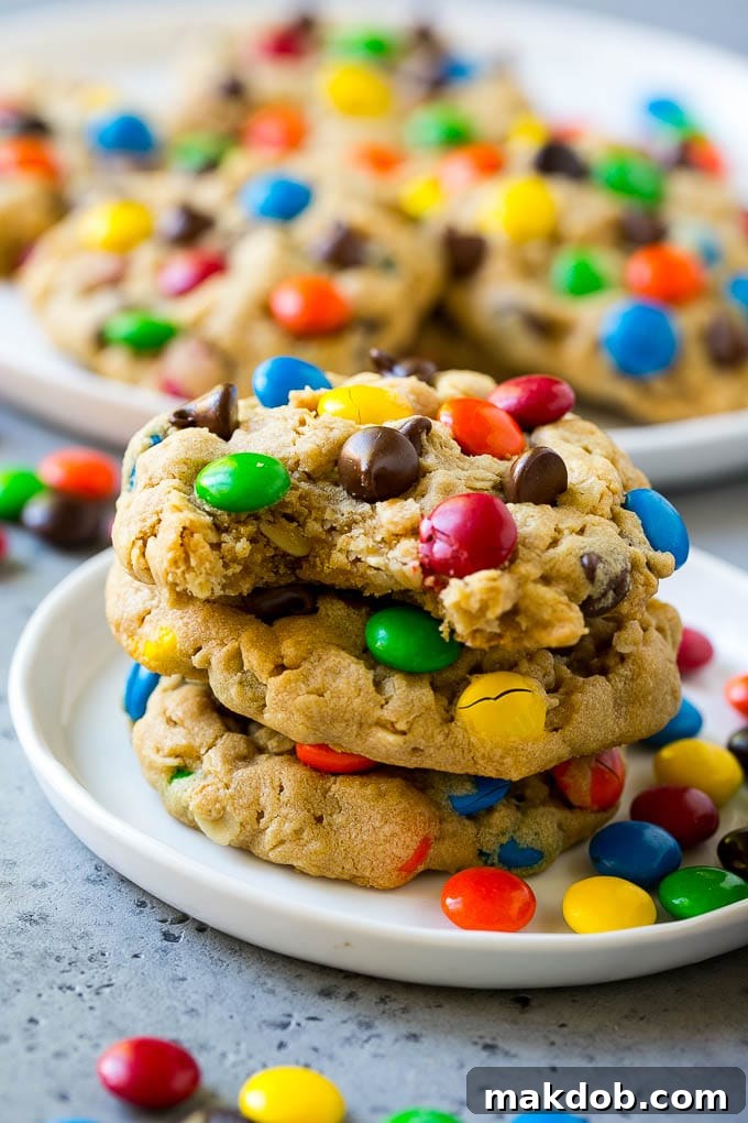 Delicious Monster Cookies Stacked with a Bite Taken A stack of golden Monster Cookies, with a perfect bite taken out of the top one, revealing its soft, chewy interior packed with chocolate and M&M's.