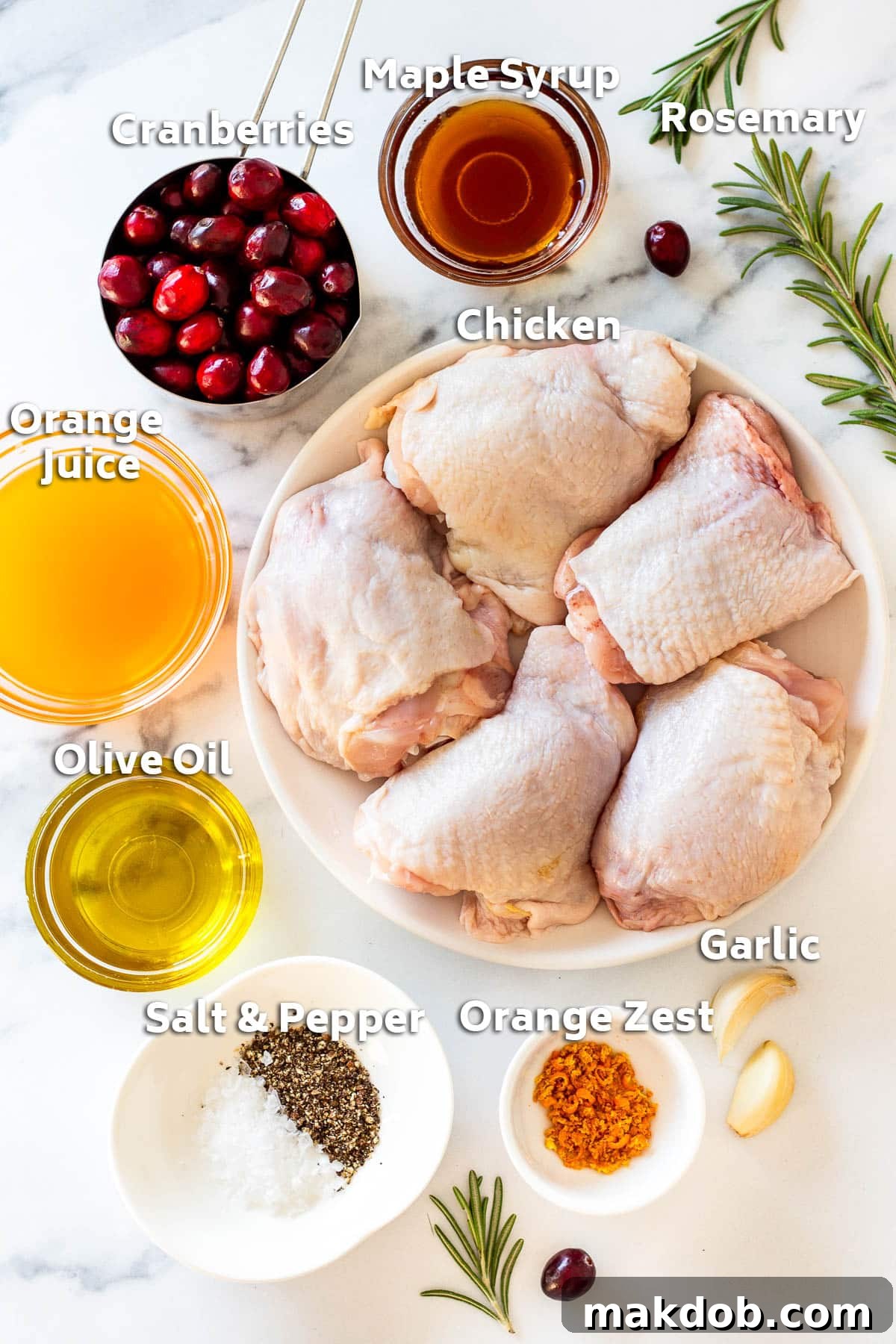 Ingredients including chicken thighs, orange juice, cranberries, maple syrup, garlic and rosemary.