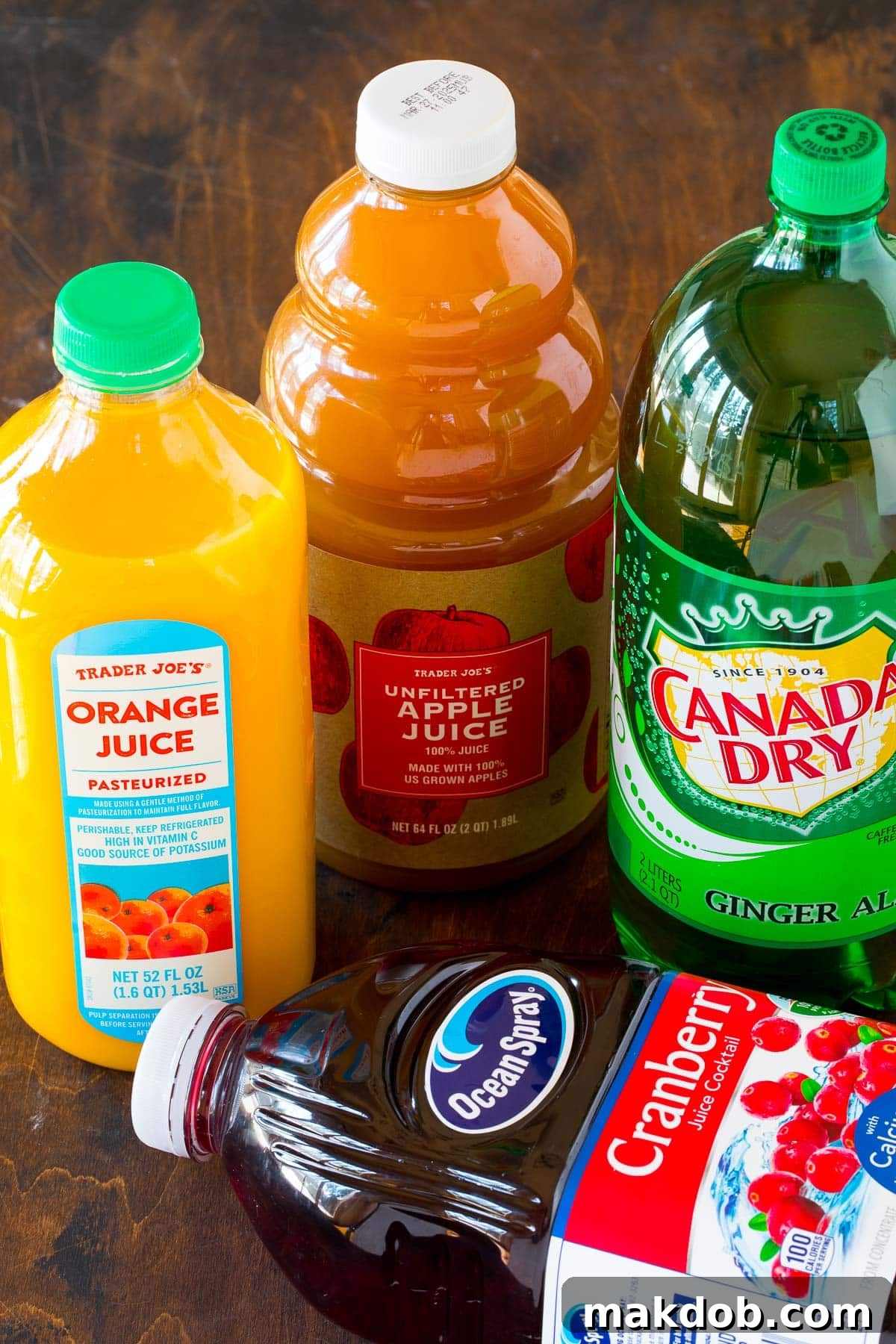 Bottles of cranberry juice cocktail, orange juice, apple juice, and ginger ale, representing the core ingredients for Thanksgiving punch.