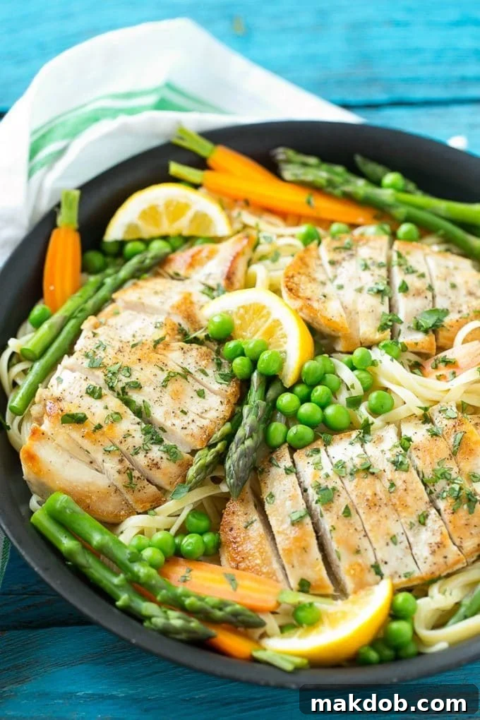 Chicken Primavera Recipe | Chicken Pasta | Vegetable Pasta #chicken #pasta #asparagus #carrots #peas #spring #dinner #dinneratthezoo A large pan filled with vibrant chicken primavera pasta, featuring chicken slices, lemon sauce, peas, carrots, and asparagus, ready to be served.