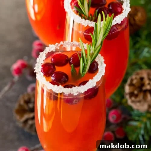 Ruby Fizz 7 A cranberry mimosa with a sugared glass rim, and a garnish of cranberries and rosemary.