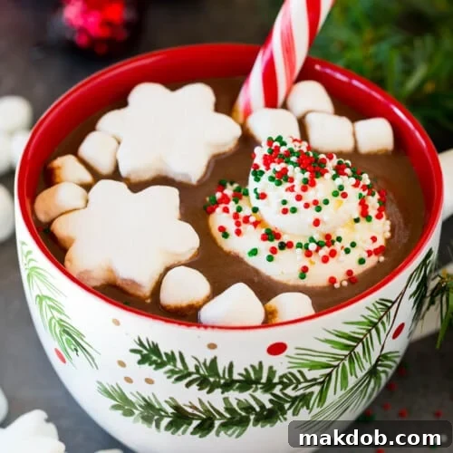 A mug of Christmas hot chocolate topped with sprinkles, whipped cream and marshmallows.