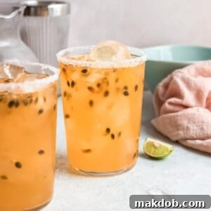 An image of two vibrant Passionfruit Palomas, garnished with lime wedges and fresh passionfruit seeds, in tall glasses.