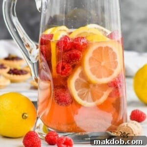 An image of a beautiful pitcher of Sparkling Rosé Sangria, filled with fresh fruit slices, ready to be served.